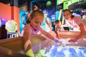 Family playing in an interactive sandbox at WonderWorks Panama City Beach